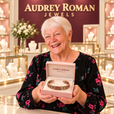 A white-haired woman presents the Florence Vine Bracelet in an Audrey Roman Jewels box inside the rose and ivory boutique.