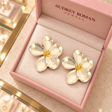 Overhead view of Cassandra silver-tone flower earrings in the Audrey Roman Jewels box on the boutique counter.