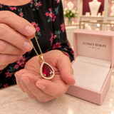 Julia Red Teardrop Pendant Necklace (gold-tone) held in the woman's hands for a close detail view inside the Audrey boutique.