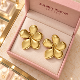Overhead view of Cassandra gold-tone flower earrings in a rose Audrey Roman Jewels box on the boutique counter.